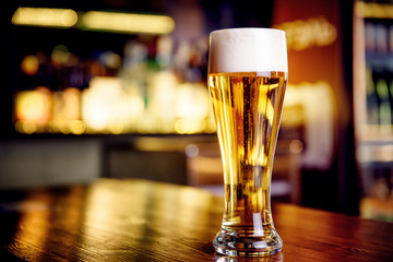 Glass of light beer on a pub with bokeh background