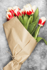 Bouquet of red-white tulips in kraft paper on a light background. Top view.