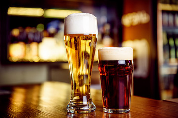 Glass of light and dark beer on a pub with bokeh background