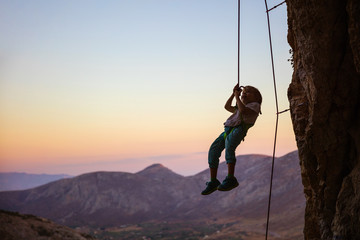 Little boy being lowered down while top rope climbing