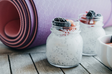Pink yoga mat and Pudding with chia seeds, yogurt and fresh fruits: Strawberries, blueberries and...