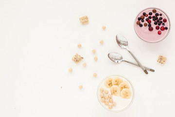 Healthy breakfast with yogurt, muesli, banana and berries on white background. Flat lay