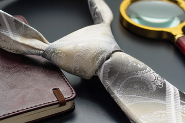 Male still life. A fountain pen with a notebook lies on a tie.