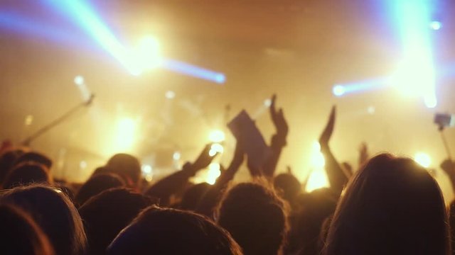 Fans waving their hands at a rock concert in slow motion in night club. 1920x1080
