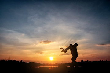 Fototapeta premium Family concept, Silhouette of father throwing son into the sky. , father and son at lake with sunset background