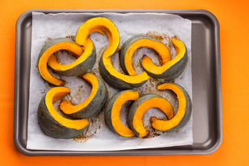 Slices of baked pumpkin on baking tray.Top view