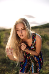 Naklejka premium beautiful dreamy blonde girl with blue eyes in a light turquoise dress lying on the stones
