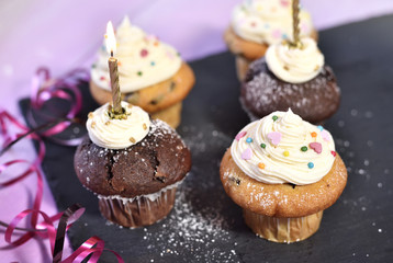 Delicious cupcakes with icing and confetti decoration. Birthday scene with burning candles.