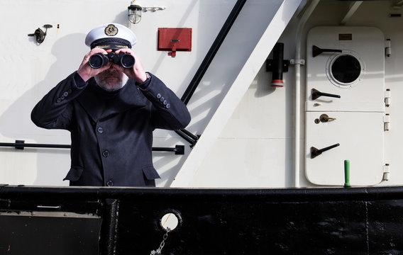 Kapit&auml;n steht mit Fernglas an der Reeling