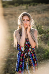 Naklejka premium beautiful dreamy blonde girl with blue eyes in a light turquoise dress lying on the stones