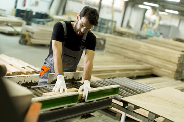 Young man works in a factory for the production of furniture