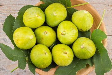 Ripe fresh green figs on wooden plate