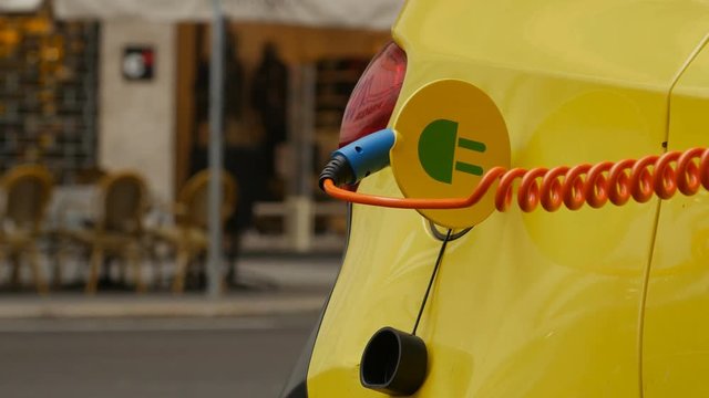 Close up of an yellow Electric Vehicle's plugged in charge port.