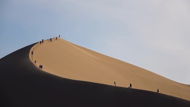 people and tourists on the highest sand duna in Kasakhstan