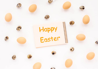 Happy Easter. Biege eggs, quail easter eggs and notebook on white background. Flat lay, top view