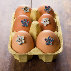 Box with six decorated eggs on wooden background