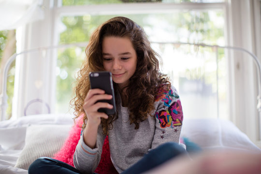 Teenager in bedroom looking at smartphone