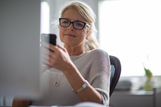 Mature Businesswoman Working On Computer And On Smartphone