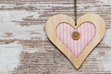 rosa Holz Herz hängt vor heller Holzwand