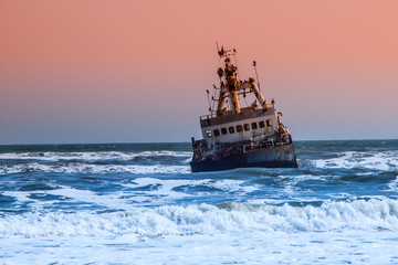 Shipwreck in wild Atlantic Ocean at Skeleton Coast, Namibia, Africa.