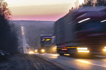 Trucks on a highway in an evening - obrazy, fototapety, plakaty