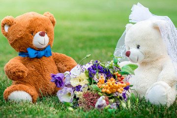 Plush bear cubs on the green grass and a beautiful bouquet