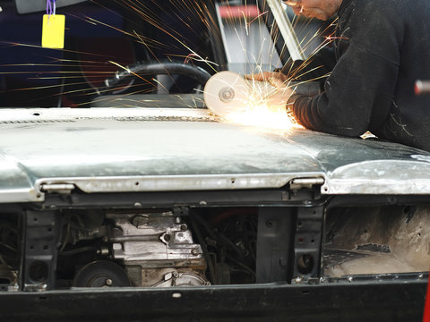 Worker Works With Angle Grinder In A Car Repair Shop