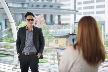 handsome businessman standing by businesswoman take photo