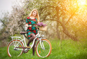 Fototapeta na wymiar Female cyclist with vintage white bicycle in spring garden
