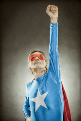 senior superhero man in blue costume red cloak and mask old portrait on textured background