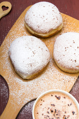 Classic donuts with powdered sugar, on wooden background