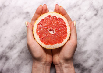 female hands keeping cut grapefruit
