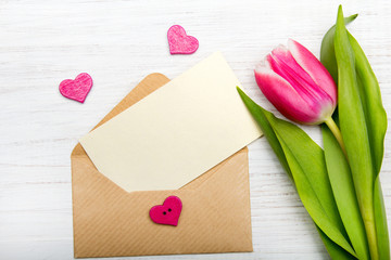 Tulip and envelope on white wooden background, copy space