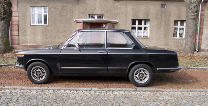 Old Black Vintage Car Parked In Front Of A House