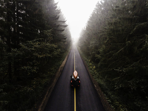 Off road vehicle with kayak on top, travelling along rural road, elevated view