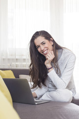 Young woman working on laptop at home. Morning scene