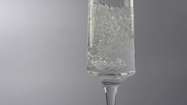 Fizzy Water Pouring Into A Glass isolated against a white background slow motion Low key