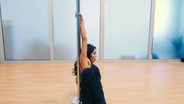 Charming woman dancing near the pylon in gym