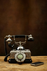 Vintage telephone on wooden table and a mobile phone.