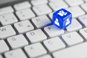 Blau farbener / blauer Würfel auf Tastatur mit Zeichen für Benutzer & Personen und Nutzergruppen