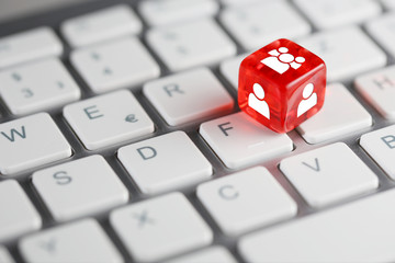 Rot farbener / roter Würfel auf Tastatur mit Zeichen für Benutzer & Personen und Nutzergruppen