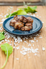 Medium Rare Fried Diced Marinated Beef on Blue Ceramic Plate on Wood Panel with Sea Salt and Vegetable Decorated.