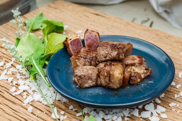 Medium Rare Fried Diced Marinated Beef on Blue Ceramic Plate on Wood Panel with Sea Salt and Vegetable Decorated.