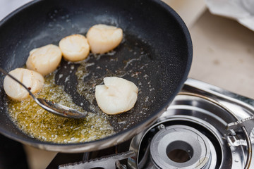 Chef Fried Scallops with Rosemary Oil in Pan with Spoon.