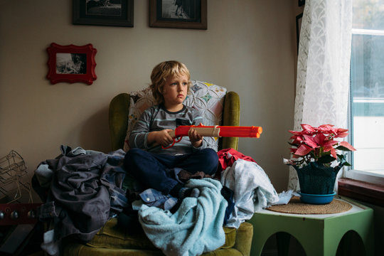 Child Sitting On Chair Holding Toy Gun