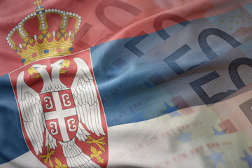 colorful waving national flag of serbia on a euro money banknotes background. finance concept