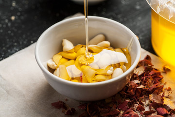 Honey trickle in bowl full of peeled peanuts in it on a wooden table