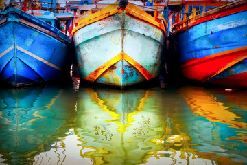 Fototapeta na wymiar Multicolored old boat in the fishing port. Colored reflections in the water. Sri Lanka. Tangalle.