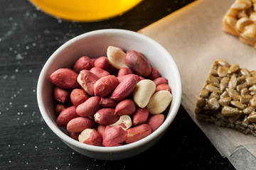 Raw unpeeled peanuts in a white ceramic bowl on a black wooden table