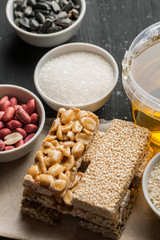 Peanut and sesame brittle with honey jar and raw ingredients in the white ceramic bowls, vertical
